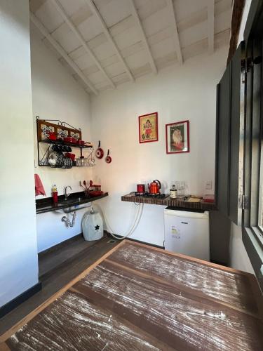 a kitchen with white walls and wooden floors at Chalés Cores da Mata in Tiradentes