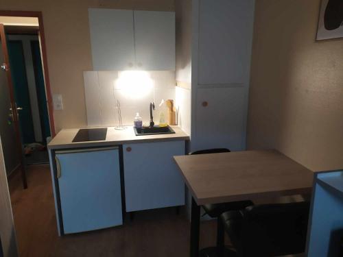 une petite cuisine avec une table et une lumière sur le comptoir dans l'établissement Studette COSY 2 couchages proche TOURS, à Tours