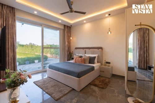 MandkaulaにあるStayVista at Olive Farms with Lawn, Pool, Bonfire & Hill Viewsのベッドと鏡と窓のある寝室