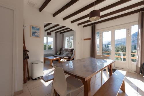 une salle à manger avec une table, des chaises et des fenêtres dans l'établissement Domaine de l'Arbizon, à Bagnères-de-Bigorre