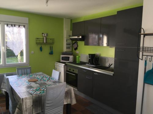 une cuisine avec des murs verts et une table ainsi qu'une cuisine avec une table dans l'établissement Location cures et vacances, à Jonzac