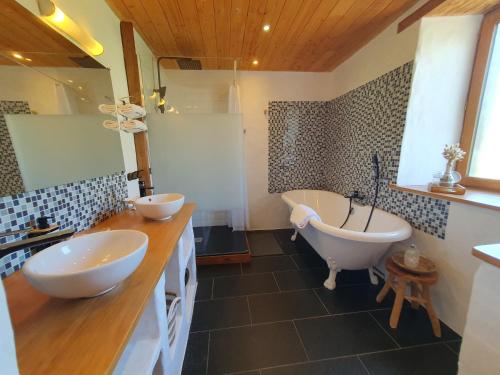 a bathroom with two sinks and a bath tub at Jolie maison en pierre avec grand jardin pour 6 in Guissény