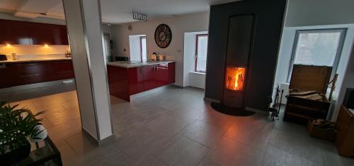 une cuisine avec des placards rouges et une horloge murale dans l'établissement Gîte Le Fortunio, à Rieutort-de-Randon