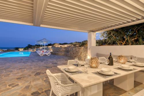 una mesa y sillas blancas con vistas a la piscina en Villa Dioni, en Santa Maria