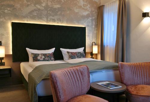 a hotel room with a bed and two chairs at Hotel Vogtland in Bad Elster