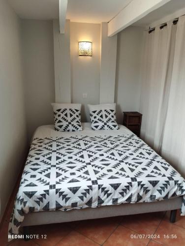 une chambre avec un lit avec une couette noire et blanche dans l'établissement Le Clos des évidences, à Domazan
