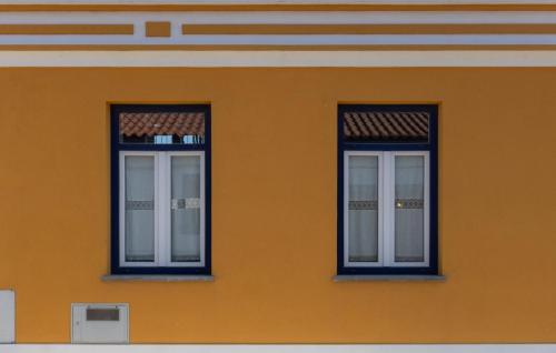 two windows on the side of a orange building at Casa Amarela Sao Luis in Odemira
