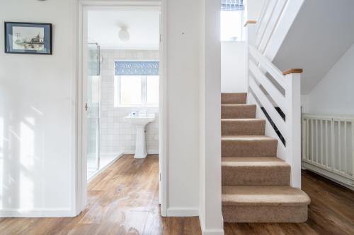 a staircase in a bathroom with white walls and wood floors at Egret 4 in South Creake
