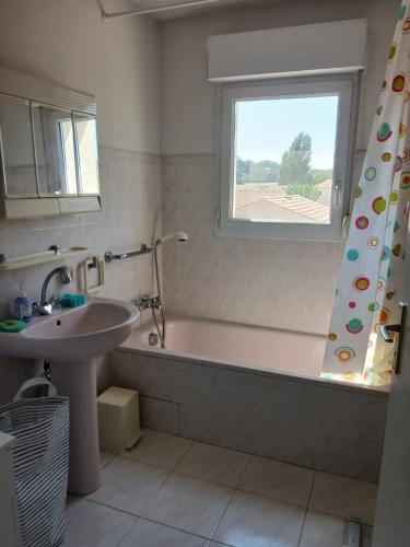 une salle de bain avec une baignoire, un lavabo et une fenêtre dans l'établissement 2 pièces terrasse 39m2 à 500m de la plage, au Lavandou