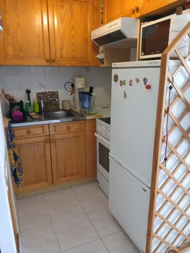 La cuisine est équipée d'un réfrigérateur blanc et de placards en bois. dans l'établissement 2 pièces terrasse 39m2 à 500m de la plage, au Lavandou