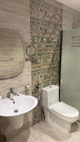 a bathroom with a white toilet and a sink at Alula Oasis1 in AlUla