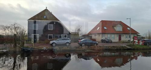 a house and cars parked next to a body of water at Studio in Amsterdam Area Horizon Hideaway in Broek in Waterland