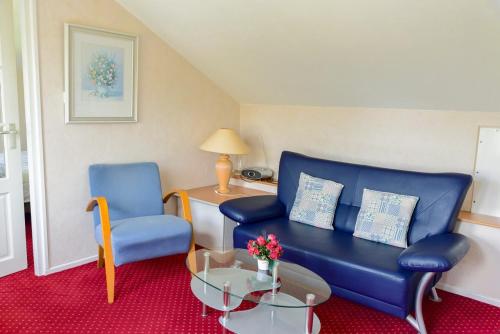 a living room with a blue couch and two chairs at B&B Vouwere in Mechelen