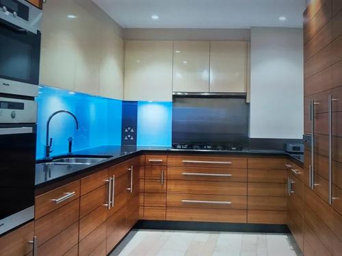 a kitchen with wooden cabinets and a sink at A Spacious Lateral Two Bedroom Two Bathroom Apartment in Surbiton