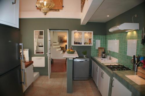 - une cuisine avec des murs carrelés verts et des armoires blanches dans l'établissement Red sun and green tea, à Saint-Jean-de-Barrou