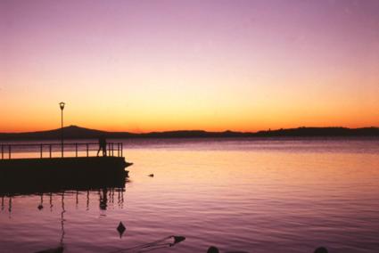 a sunset over a body of water with a pier at Hotel Cavalieri in Passignano sul Trasimeno