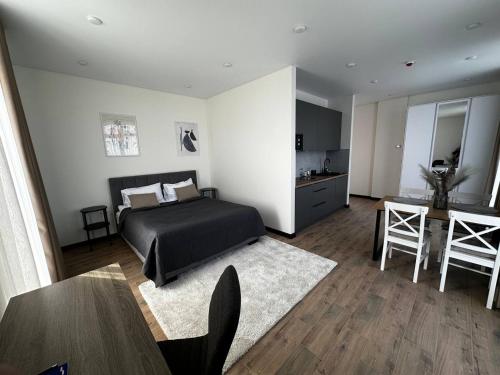 a bedroom with a bed and a table and a kitchen at Smart House Apartments in Lviv