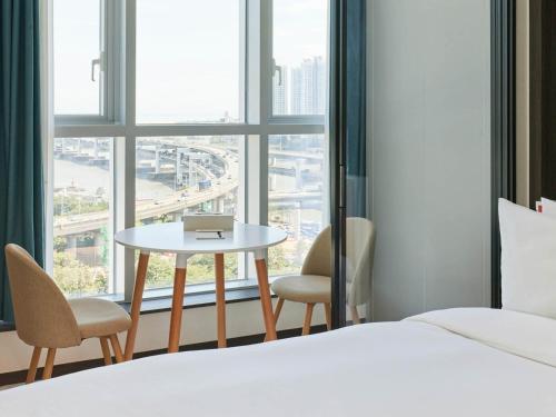 a bedroom with a table and chairs and a window at NewCZ Centum Hotel in Busan