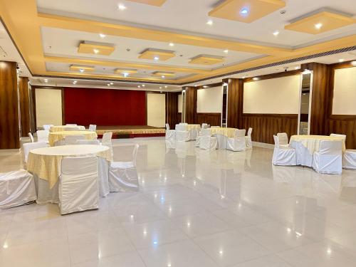 a banquet hall with white tables and white chairs at Hotel Riddhi Inn in Udaipur