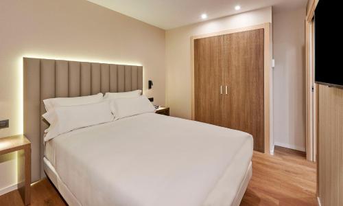 a bedroom with a large white bed and a sliding door at NH Andorra la Vella in Andorra la Vella