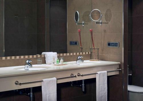 a bathroom with two sinks and a mirror at NH Andorra la Vella in Andorra la Vella
