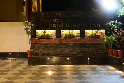 a welcome to hotel radiation inn sign on a brick wall with plants at Hotel Riddhi Inn in Udaipur