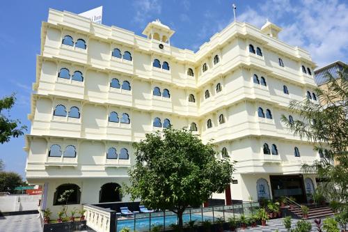 a white building with a tree in front of it at Hotel Riddhi Inn in Udaipur