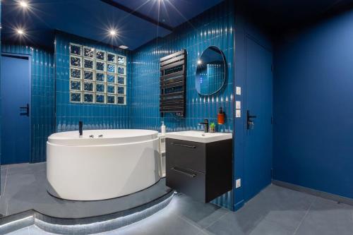 a blue bathroom with a tub and a sink at Arc de Triomphe romantic suite JACUZZI saphir in Paris
