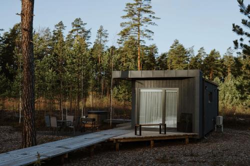 a small cabin with a wooden deck in the woods at ForRest Glamp Saulkrasti in Saulkrasti