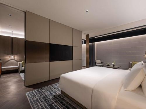 a bedroom with a large white bed and a tv at Pullman Quanzhou Shuitou in Quanzhou