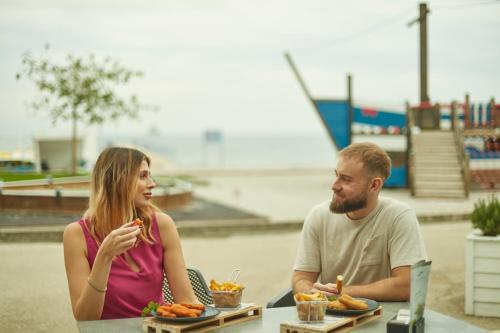 a man and a woman sitting at a table with food at Villas - Hotel & Resort Adria Ankaran in Ankaran