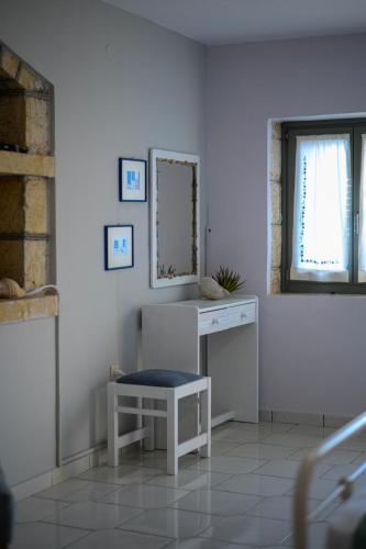 a white bathroom with a mirror and a chair at Κοχύλι in Kotrónion