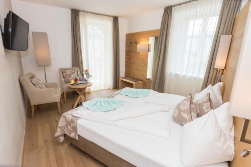 a hotel room with a large bed and a chair at Das Alte Rathaus in Egna