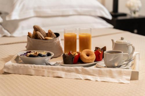 un vassoio di prodotti per la colazione e bevande su un letto di Plaza Resort ad Anávissos