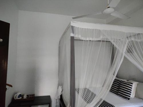 a bedroom with a bed with white curtains at Villa Uppugama in Etagama