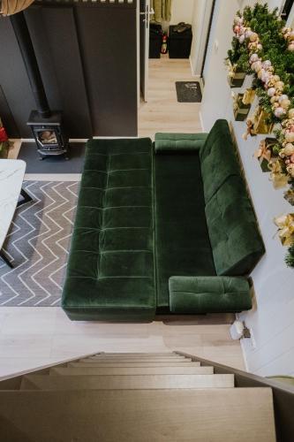 a green couch sitting in the middle of a room at ForRest Glamp Saulkrasti in Saulkrasti