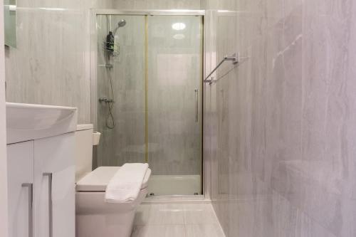 a white bathroom with a shower and a toilet at Sea Breeze - 1 bedroom flat in Brighton & Hove