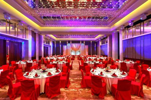 a large banquet hall with tables and red chairs at Sheraton Guangzhou Hotel in Guangzhou