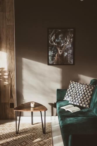 a living room with a green couch and a table at Sowie Chatki - domki z widokiem na Góry Sowie in Sokolec