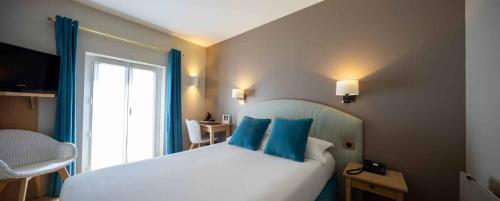 a bedroom with a bed with blue pillows and a window at Hôtel de la Plage - Saint Jean de Luz in Saint-Jean-de-Luz