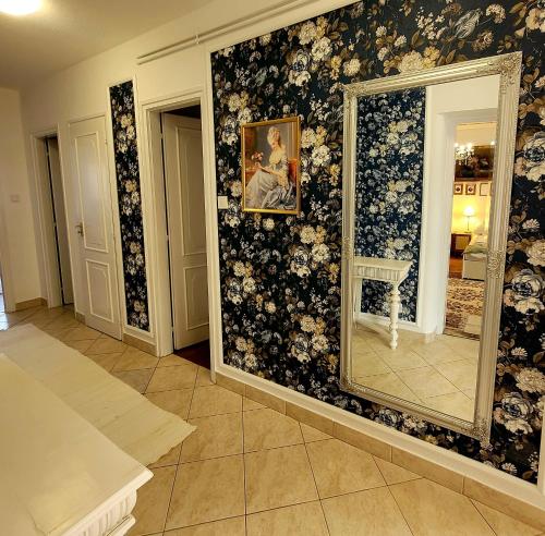 a room with a mirror on a wall with flowers at Bonjour Vendégház in Nyíregyháza