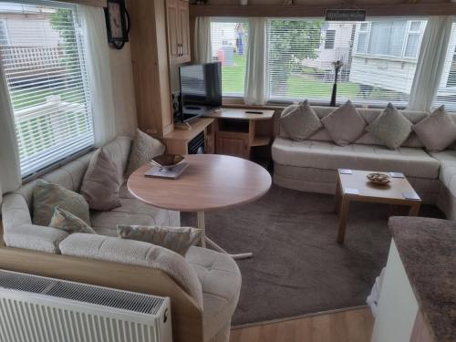 a living room with a couch and a table at S212 6 BERTH DELUXE GOLDEN PALM CHAPEL ST LEONARDs in Chapel Saint Leonards
