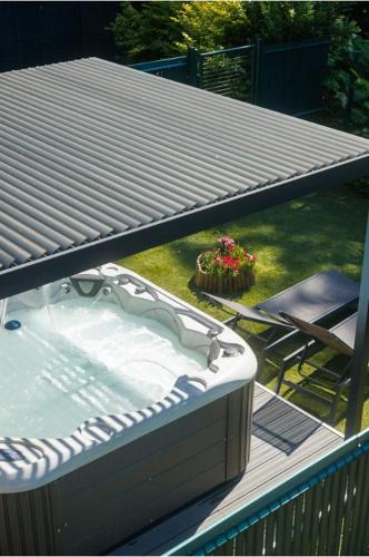 a hot tub on a deck with a table and a chair at Résidence Les Rives de la Fecht - Colmar Ouest in Ingersheim