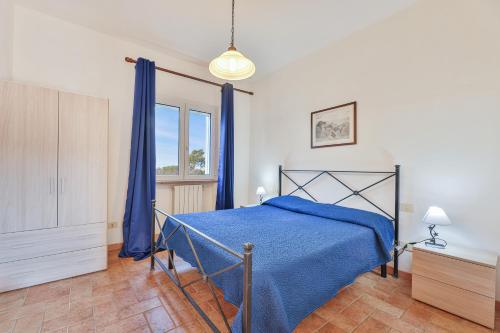 Un dormitorio con una cama azul y una ventana. en Appartamenti Le Prade - Goelba, en Portoferraio