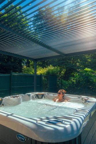 a woman in a hot tub under a pergola at Résidence Les Rives de la Fecht - Colmar Ouest in Ingersheim