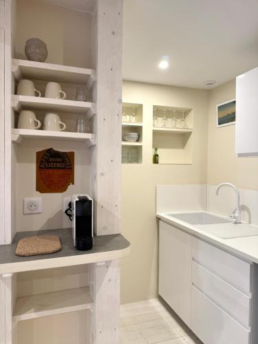 La cuisine est équipée de placards blancs, d'un évier et d'un comptoir. dans l'établissement Appartement entre mer et montagne, à Gréolières