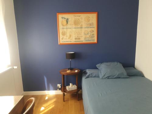 - une chambre dotée d'un mur bleu avec un lit et une table dans l'établissement Chambre confortable dans un appartement lumineux, à Toulouse