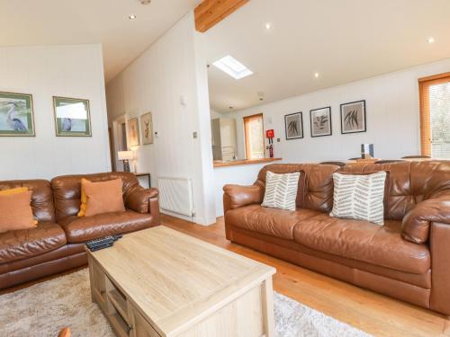 a living room with brown leather couches and a table at 6 Hedgerows in Looe