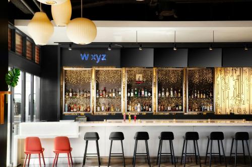 a bar with red stools in front of a bar at Aloft El Segundo - Los Angeles Airport in El Segundo