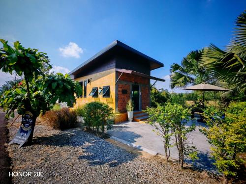 a house with a black roof and a yard with trees at Leisure in Ban Rong Koet